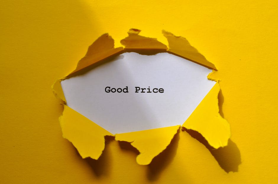 A torn yellow paper background with a large, irregular hole revealing a white piece of paper inside. The white paper displays the words 'Good Price' typed in black text. The torn edges of the yellow paper are jagged and curled outward, creating a layered, three-dimensional effect. The background surrounding the torn paper is a solid, vibrant yellow. The scene suggests a concept related to affordable moving or removal services, with the focus on transparency and value, aligning with home relocation and furniture transport themes handled by Man with Van Feltham.